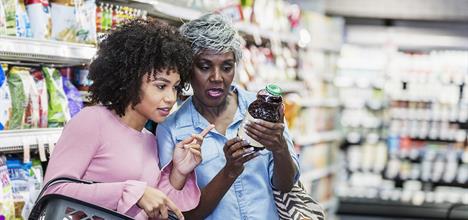 Mujeres en el mercado leyendo la etiqueta de un producto.